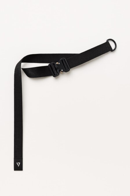 Cintura nera in nylon resistente con fibbia tattica in metallo e anello a D laterale. Il design è minimalista e tecnico, adatto a look streetwear o utility. Sul capo libero della cintura è visibile un'etichetta con logo bianco su sfondo nero. Sfondo bianco uniforme.<br /><br /><br /><br /><br /><br /><br /><br /><br /><br />